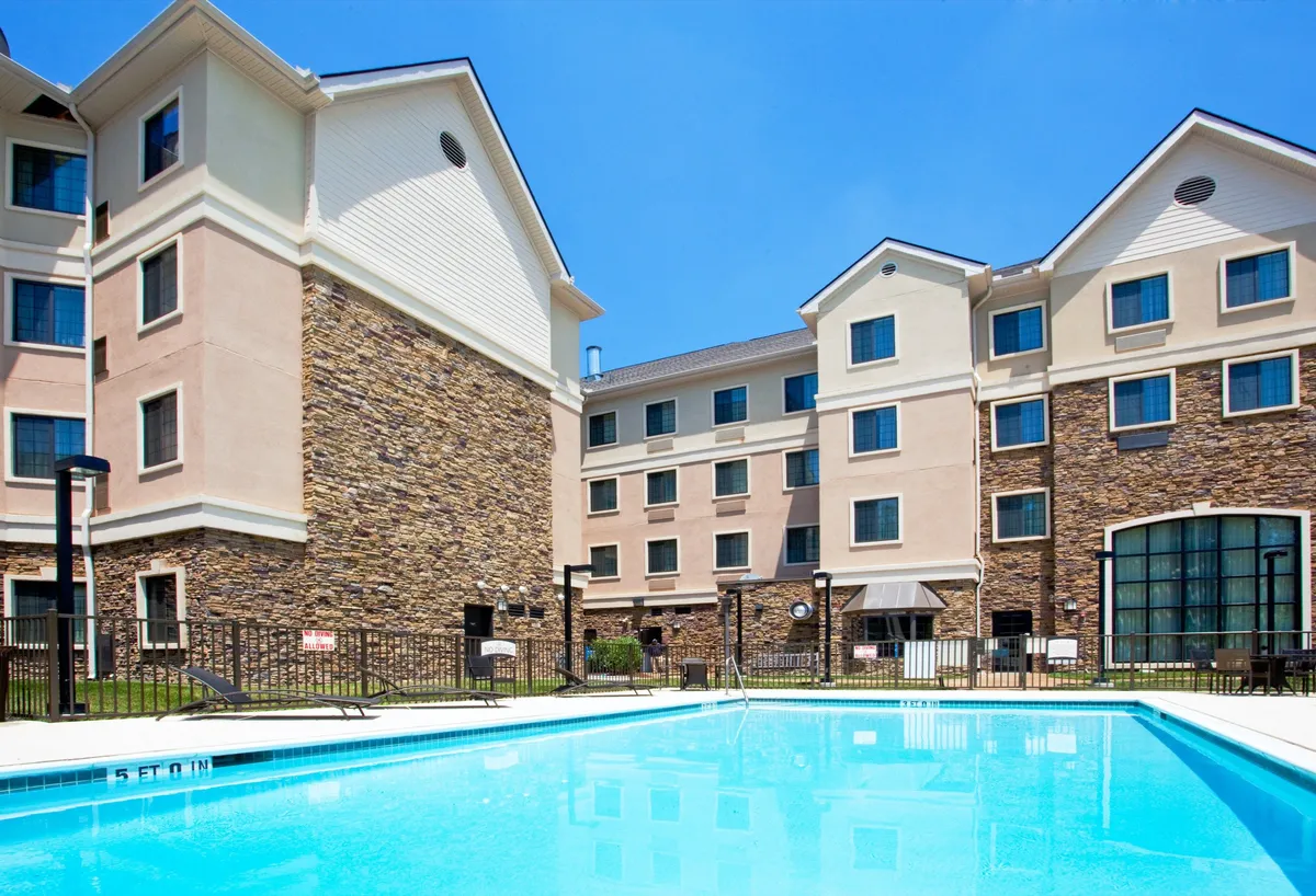 An inviting outdoor swimming pool bordered by a stone facade and overlooked by the building's windows. The space is perfect for swimming, sunbathing, or relaxing with friends, and conveys a resort-like atmosphere ideal for leisure and downtime.
